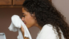 A woman smelling a clean shirt after she cleaned it from oil stain
