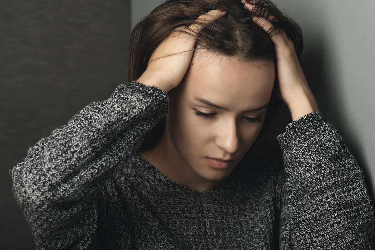 Woman holding head showing stress and lack of sleep