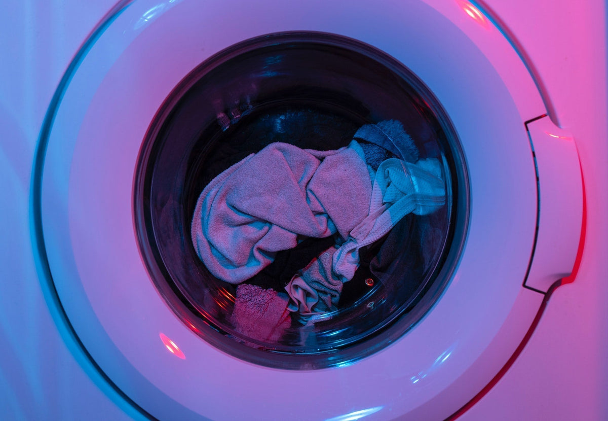 Close up of laundry inside of a washing machine in neon lighting.