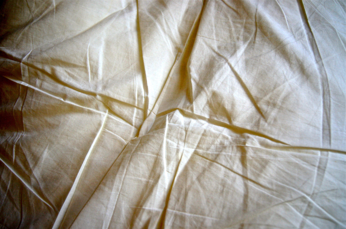 Yellow stained and wrinkled sheets on a bed.