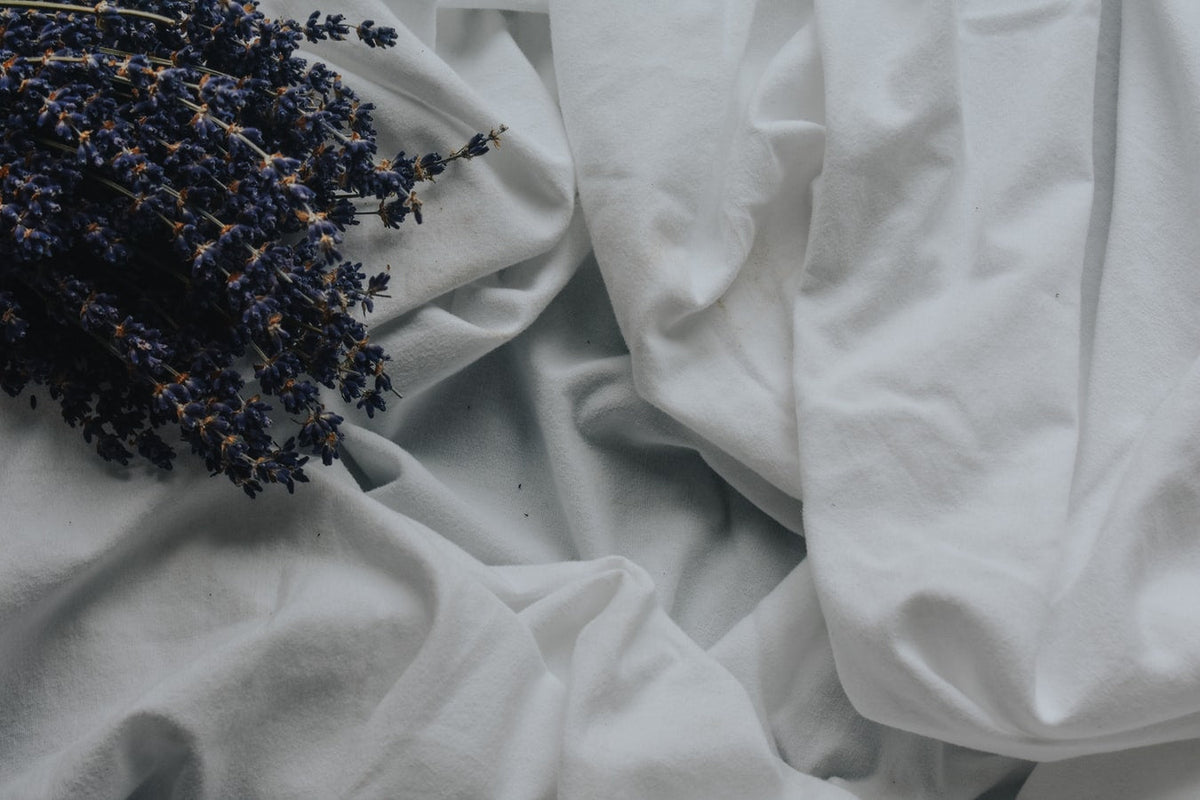 A bundle of dried lavender resting on top of rumpled white fabric, creating a serene and natural aesthetic.