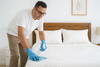 An image of a man spraying alcohol on bed sheets