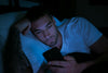 Man using smartphone in bed at night affecting sleep quality