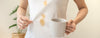 Person holding a mug with visible coffee stains on a white shirt.