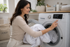 A woman setting t he washing machine to wash the bedsheets.