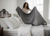 A woman changing the white bedsheet with a new gray silk sheet.