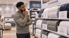 A black man deciding which comforter to buy in the store.