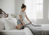 Woman on the bed putting a new gray bedsheet.