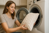 An image of a woman loading a throw pillow into the washing machine