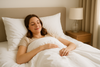 An image of a woman laying in bed thinking how comfortable hotel sheets are