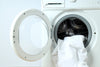 White bedding being loaded into front-load washing machine