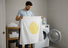 A man holding a white sheet with yellow stain.