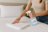 Spraying laundry sanitizer to a pillow case on the bed