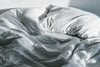 Unmade bed with wrinkled white sheets and pillows