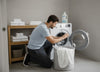 A man going to wash a sheet in the washing machine.