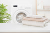Folded bedsheets beside washing machine for easy bedding care