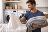 A man going to laundry the bedsheets.