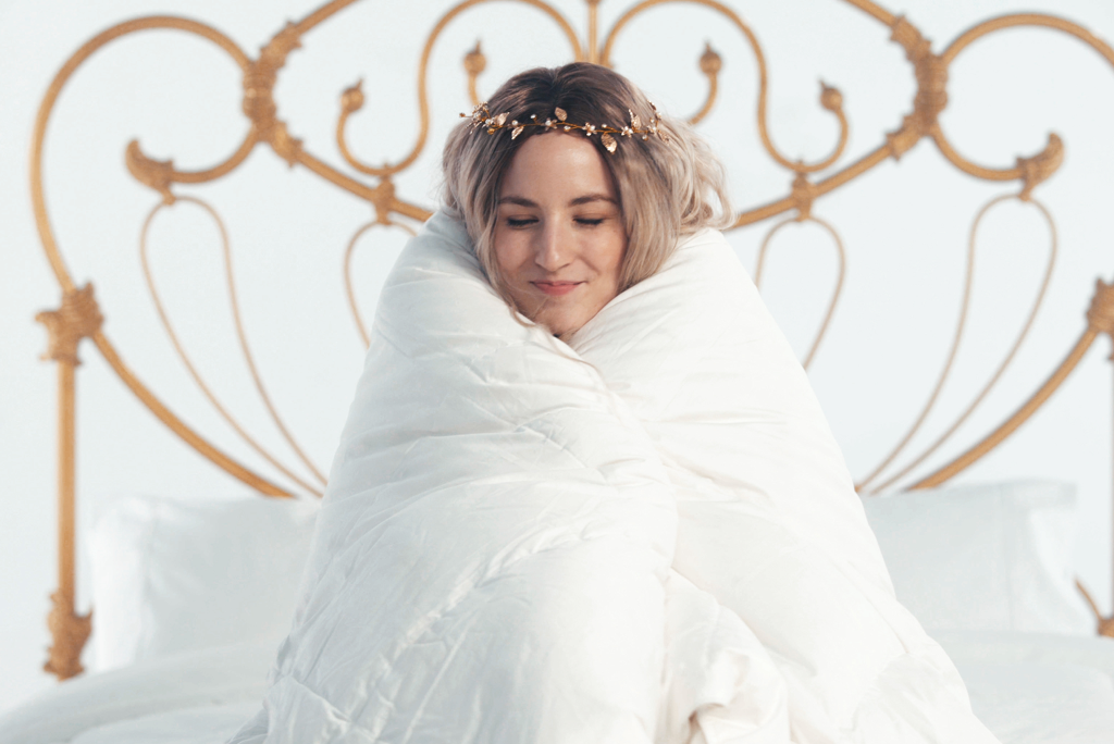 Woman wrapped in soft white comforter for cozy sleep