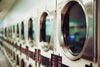 Rows of washers and dryers inside of a laundromat.