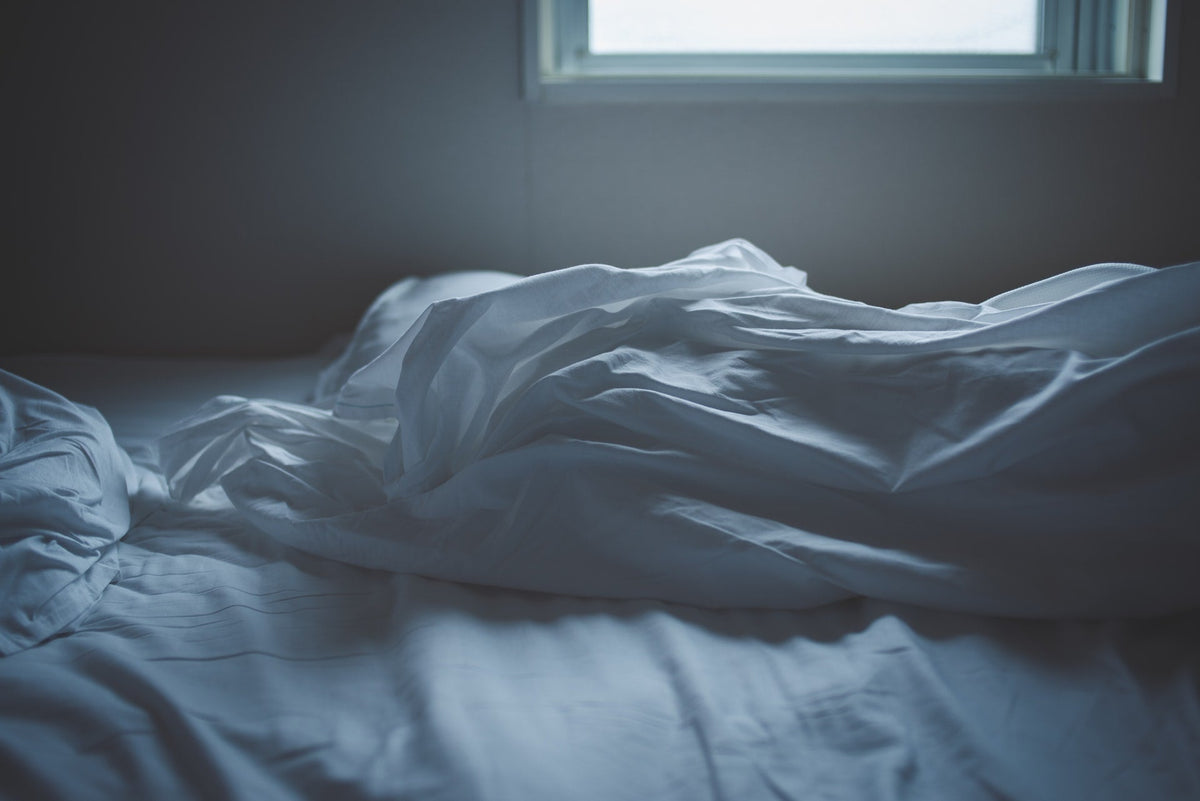 White sheets on a bed being under natural lighting.