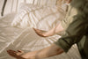 Hands smoothing soft cotton bedding for a neatly made bed