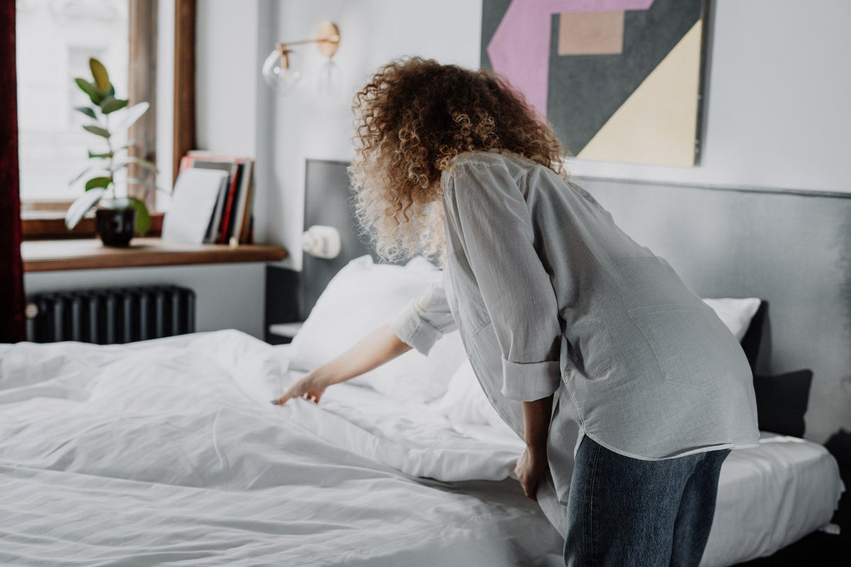 Curly hair woman making the bed.