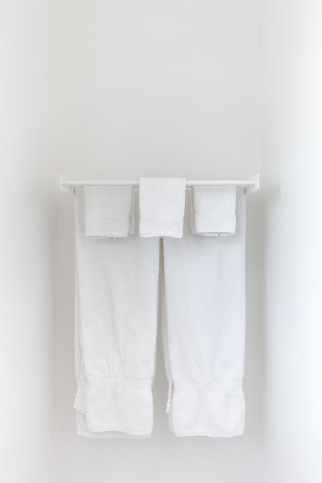 White bath towels hanging on a white bar.