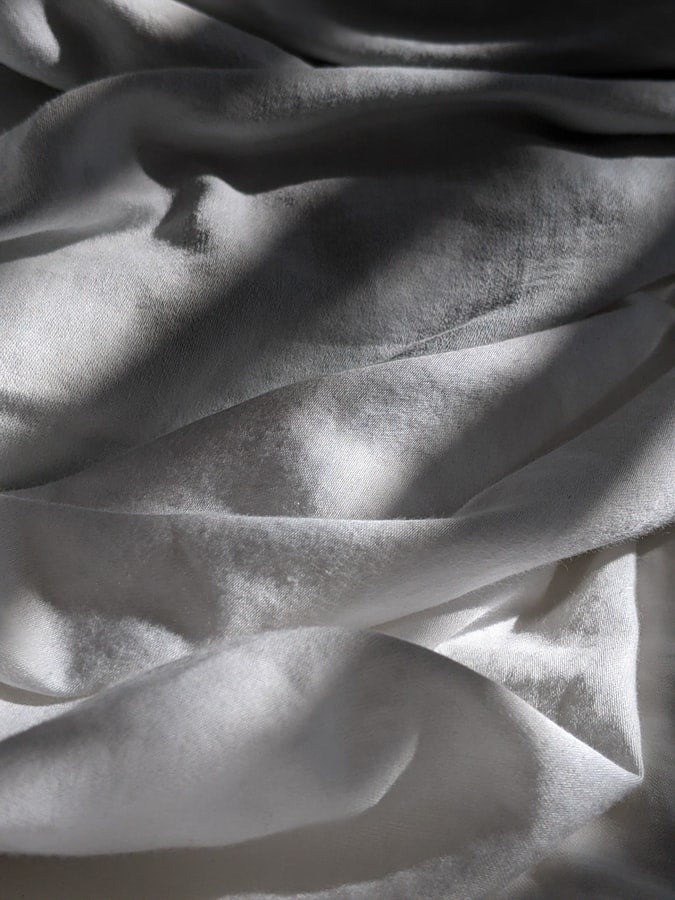Pile of white sheets on a bed.
