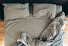 Unmade bed with wrinkled cotton sheets and pillows