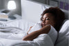 Woman sleeping comfortably in bed under white bedding at night