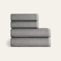 Stack of four gray textured towels on a white background