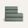 Stack of four folded green checkered towels on a light gray background