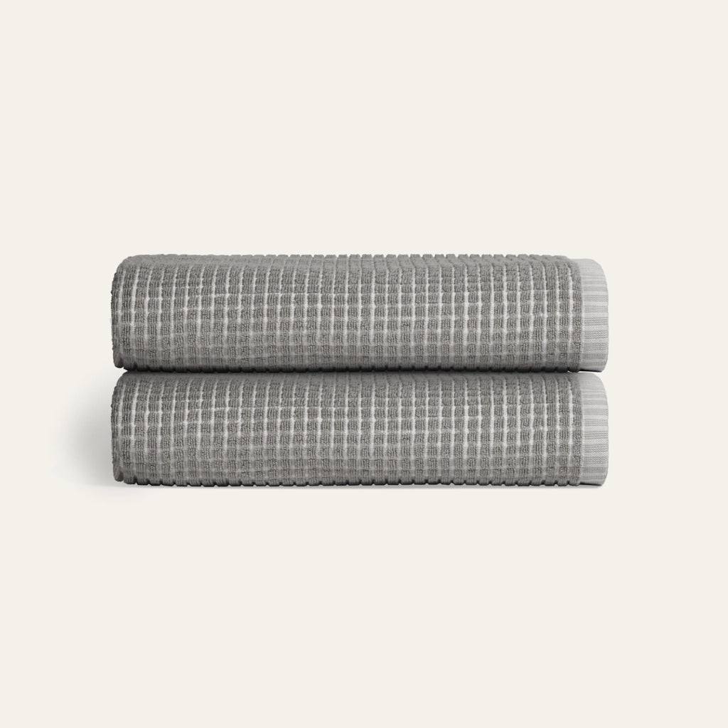 Two folded gray textured blankets stacked on a light beige background