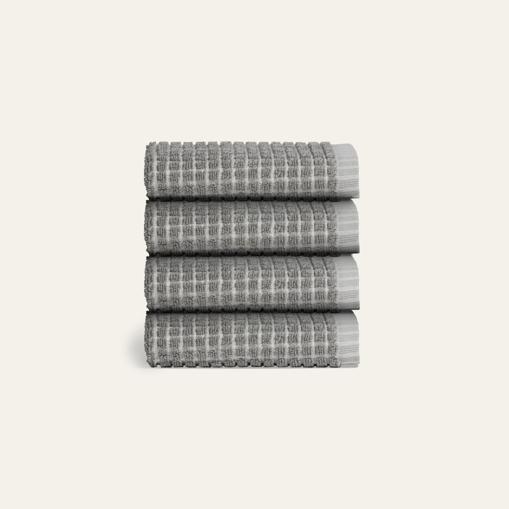 Stack of four gray textured towels on a light gray background