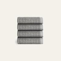 Stack of four gray textured towels on a light gray background