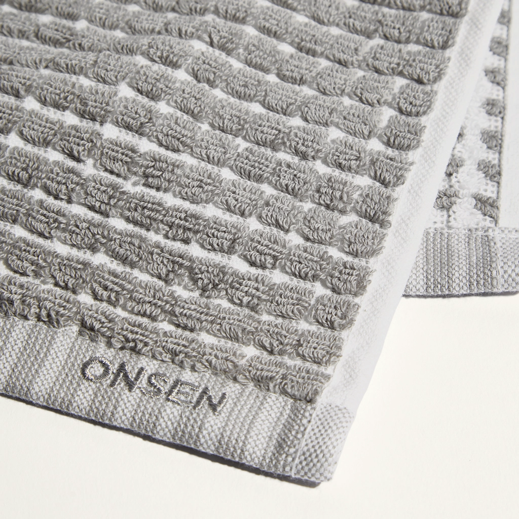 Gray textured bath mat with 'Onsen' branding on a white background