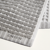 Gray textured bath mat with 'Onsen' branding on a white background