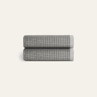 Two folded gray textured towels on a light beige background