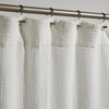 White textured shower curtain with a silver curtain rod on a gray background