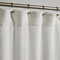 White textured shower curtain with a silver curtain rod on a gray background