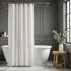 Bathroom with a freestanding bathtub, white shower curtain, and wooden stool with a plant.