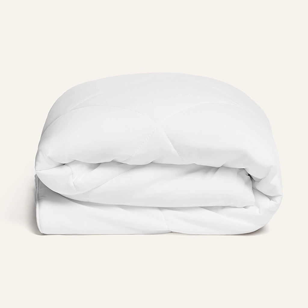 Folded white comforter on a light beige background