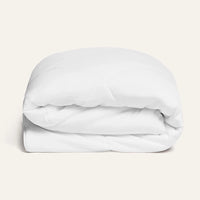 Folded white comforter on a light beige background