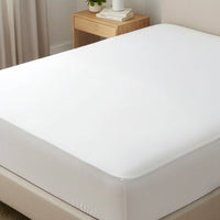 White mattress protector on a bed in a bedroom setting