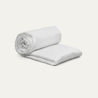 Rolled-up white blanket on a light gray background