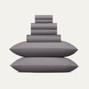 Stack of gray pillows and bed sheets on a white background
