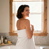 Woman wrapped in a towel standing in a bathroom with a window in the background