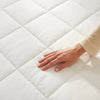 Hand touching a white quilted mattress to check its softness