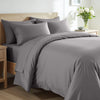 Gray bedding set on a bed in a bedroom with wooden headboard and nightstands.