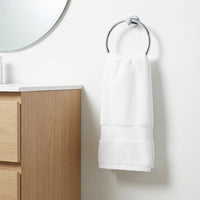 White towel hanging on a silver towel ring in a bathroom.